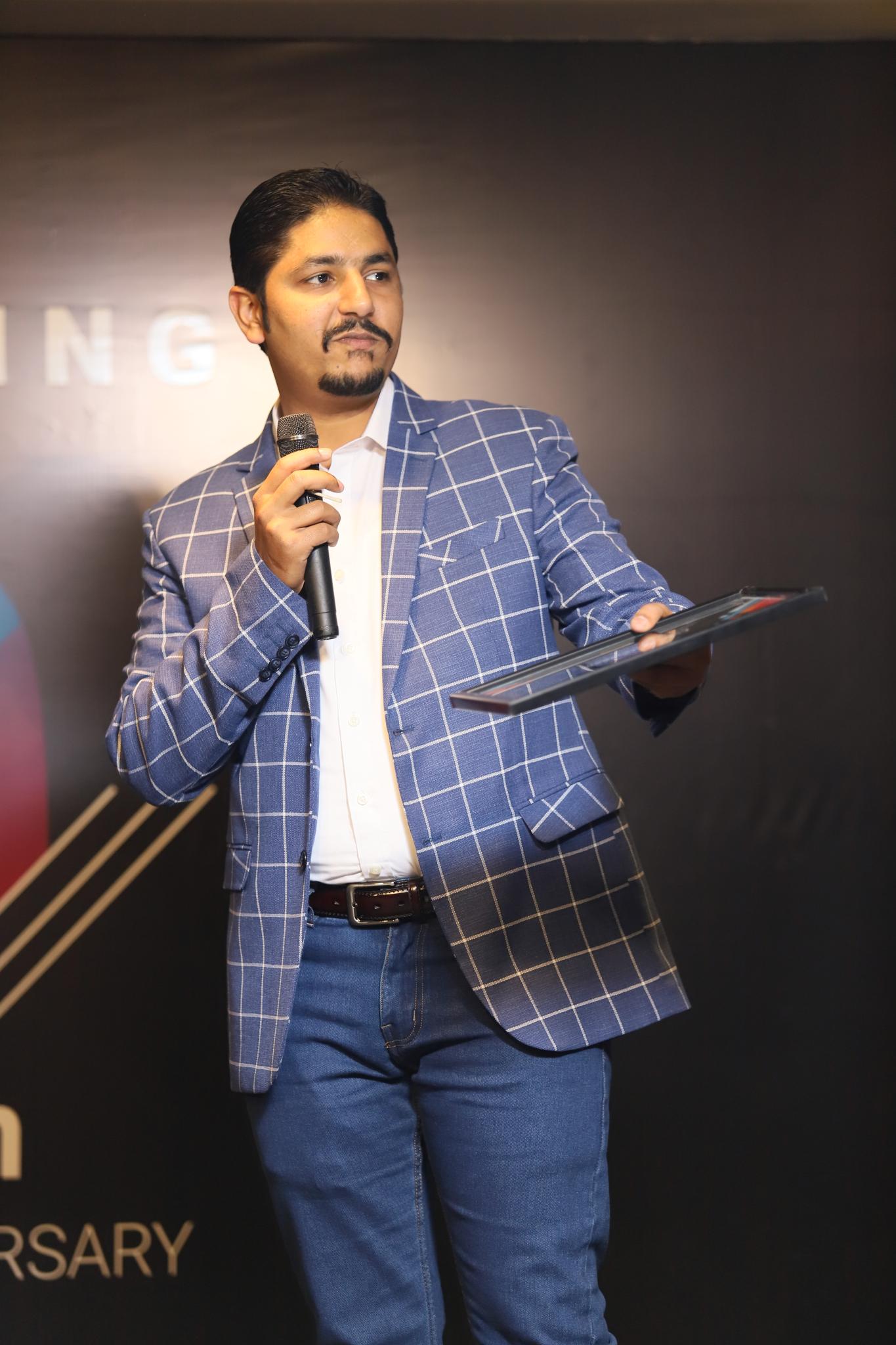 Afzal presenting on stage with a microphone and tablet